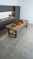 Modern minimalist kitchen with wooden dining table featuring fresh vegetables and healthy ingredients for meal preparation and cooking.