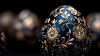 Ornate Easter egg with intricate gold and silver floral design on deep blue background featuring delicate flowers and swirling patterns in traditional European style.