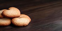 Heart shaped butter cookies on dark wooden background with copy space, selective focus. Fresh homemade sweet pastry for Valentine's day or romantic occasion.
