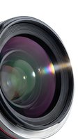 Professional camera lens with colorful optical coatings and light reflections on white background for photography equipment and technology concepts.