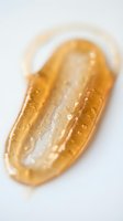 Transparent golden gel serum or cosmetic oil droplet with water droplets on white background, suitable for skincare and beauty product packaging design.
