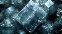 Macro shot of natural cubic halite salt crystals with translucent structure against dark background showing mineral formation and geometric patterns.
