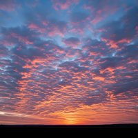 Dramatic sunset sky with vibrant pink and orange clouds over silhouetted horizon landscape for nature photography and scenic backgrounds.