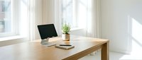 Modern minimalist home office workspace with computer monitor on wooden desk near bright window with natural light for remote work productivity.