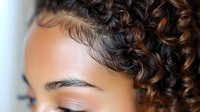 Young African American woman with natural curly hair and flawless makeup showcasing professional beauty and skincare results for cosmetic industry.
