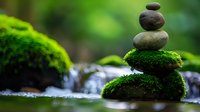Zen stone stack with moss in peaceful forest stream setting for meditation and wellness concepts.