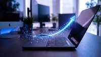 Modern laptop computer with glowing blue digital data stream flowing from screen in contemporary office workspace for technology and connectivity concepts.