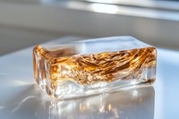 Luxurious amber liquid splash frozen in clear glass block on white surface with natural lighting, creating dynamic fluid motion and reflective highlights.