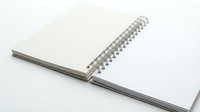 Open spiral notebook with blank white pages and metal wire binding on clean white background for office supplies and stationery design projects.