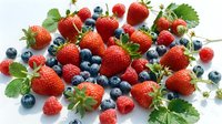 Fresh mixed berries with strawberries, blueberries and raspberries scattered on white background. Healthy organic fruit harvest for smoothies and desserts.