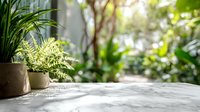 Marble table with potted plants against blurred green garden background, creating serene outdoor living space for relaxation.