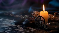 Mystical pentagram symbol with burning candle and tarot cards creating atmospheric occult scene for spiritual practices and esoteric rituals.