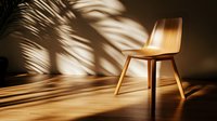 Modern wooden chair in warm sunlight with palm leaf shadows casting dramatic patterns on minimal beige wall and floor, creating contemporary interior design scene.