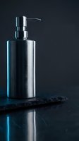 Stainless steel soap dispenser on dark marble surface with dramatic lighting and reflection for modern bathroom design and luxury home decor.