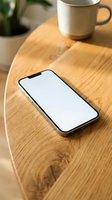 Smartphone with blank white screen on wooden table next to coffee cup for app mockup and digital presentation design.