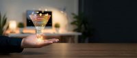 Hand holding glowing funnel with coins flowing down representing sales conversion process and financial growth in modern office setting.
