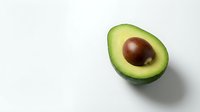Fresh ripe avocado half with pit on clean white background, healthy organic fruit for cooking, nutrition and diet concepts.