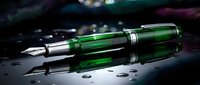Luxury green fountain pen with chrome accents resting on reflective surface with water droplets, suitable for business, writing, and premium product photography.