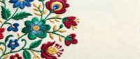 Colorful floral embroidery with blue and red flowers on cream fabric background. Traditional needlework craft design for textile and home decor projects.