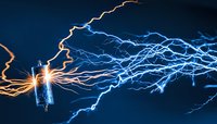Dramatic electrical discharge from high voltage component with orange and blue lightning bolts against dark background, power and energy concept.