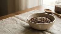 Organic chia seeds in ceramic bowl on rustic wooden table with natural lighting for healthy cooking and superfood nutrition concepts.