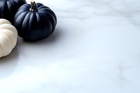 Black and white pumpkins on marble background with copy space, minimal autumn composition for seasonal marketing and social media content.