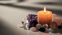 Burning candle surrounded by healing crystals and gemstones creating peaceful meditation atmosphere for wellness and spiritual practices.