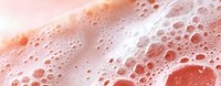 Macro shot of pink foam bubbles creating abstract texture with light and shadow play, soft pastel background for cosmetic and skincare products.