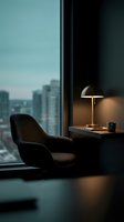 Modern high-rise office or apartment interior with dark upholstered chair, brass desk lamp, and panoramic city skyline view through floor-to-ceiling windows. Contemporary workspace design.
