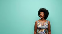 Young African American woman with natural curly hair wearing floral sleeveless dress against turquoise background, looking upward thoughtfully for portrait and lifestyle use.
