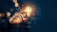 Businessman holding glowing light bulb with digital code background, representing innovation, creativity, and smart business solutions for technology concepts.