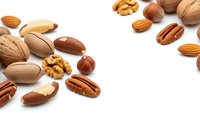 Mixed nuts collection with almonds walnuts pecans hazelnuts and pistachios scattered on white background for healthy snacking and cooking ingredients.