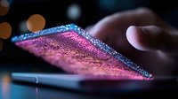 Glowing pink and blue sparkles illuminate smartphone screen edge in dark setting with bokeh lights, creating magical technology atmosphere with finger touch.