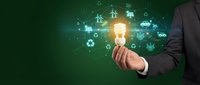 Businessman holding glowing lightbulb with green energy icons including wind turbines, solar panels and recycling symbols for sustainable business solutions.