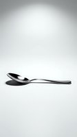 Single stainless steel spoon with polished finish isolated on white background, casting sharp shadow. Suitable for restaurant, dining, kitchenware, and tableware design projects.