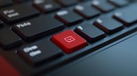 Red email button on black computer keyboard illuminated with dramatic lighting, close-up macro shot showing technology detail and communication concept.