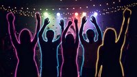 Silhouettes of people dancing with raised hands at night party with colorful lights and string bulbs creating festive atmosphere for celebration events.