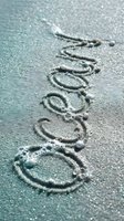 Word ocean written in wet sand on a beach shore with sea foam bubbles, top view close-up for summer travel and vacation concepts.