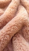 Soft pink faux fur fabric texture with fluffy pile creating cozy warmth for home decor and fashion design projects.