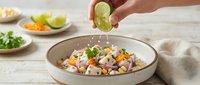 Ceviche with fresh lime being squeezed over shrimp, vegetables, and citrus in a bowl, ready for cooking or marinating.