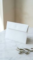 White blank envelope on marble surface with olive branch for wedding invitations and stationery mockup design.