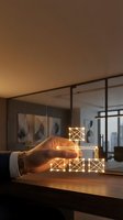 Hand stacking illuminated geometric wireframe cubes on wooden desk in modern office space with city skyline view, representing business growth and strategic planning.