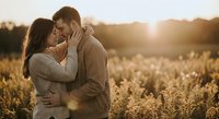 Young couple embracing intimately in golden wheat field during sunset, romantic moment in countryside for wedding, engagement and love concepts.