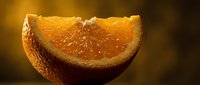 Fresh orange slice with juicy pulp and textured peel on warm golden background for healthy eating and citrus fruit concepts.