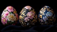 Ornate Easter eggs featuring delicate floral patterns in pink and blue on black background with gold accents, arranged in decorative composition on dark fabric.