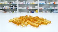 Golden omega-3 fish oil capsules scattered on white pharmacy counter with blurred medicine shelves background for health supplement marketing.