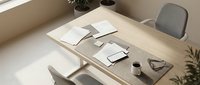 Modern minimalist workspace with wooden desk, gray office chairs, notebooks, coffee cup and plants creating productive home office environment for remote work.