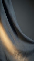 Elegant gray linen fabric with warm golden light creating dramatic shadows and texture for interior design and textile backgrounds.