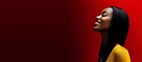 Young African American woman with long straight black hair wearing yellow top against vibrant red background, profile view with joyful expression and closed eyes.