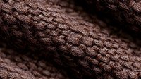 Close up view of brown knitted wool texture showing detailed pattern and stitches in warm natural fiber material, suitable for fashion and craft backgrounds.